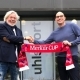Uwe Vaders (links) und Dirk Hendrik Lehner (rechts) schütteln sich die Hände und halten Merkur Cup Schal