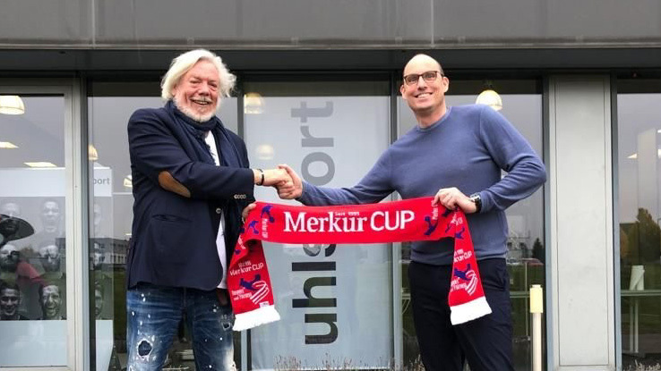 Uwe Vaders (links) und Dirk Hendrik Lehner (rechts) schütteln sich die Hände und halten Merkur Cup Schal